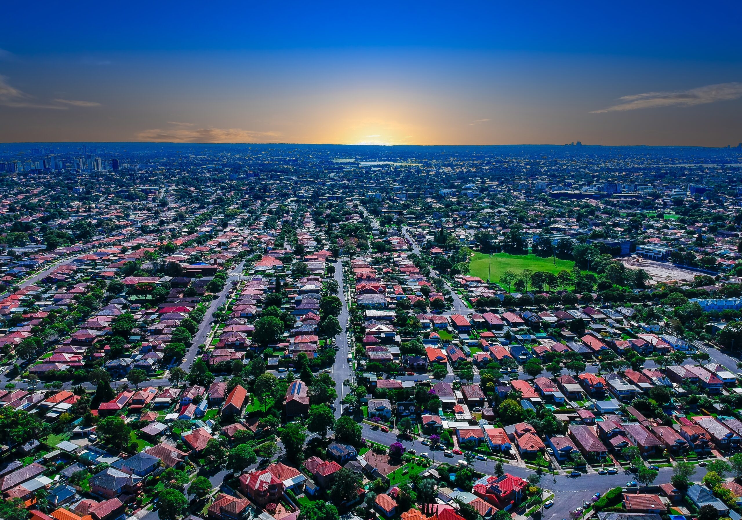 Aerial view of Melbourne suburb, displaying rows of houses with the city in the background as the sun sets. Melbourne is one of the most expensive residential housing markets in Australia, as outlined in the June 2025 economic update.